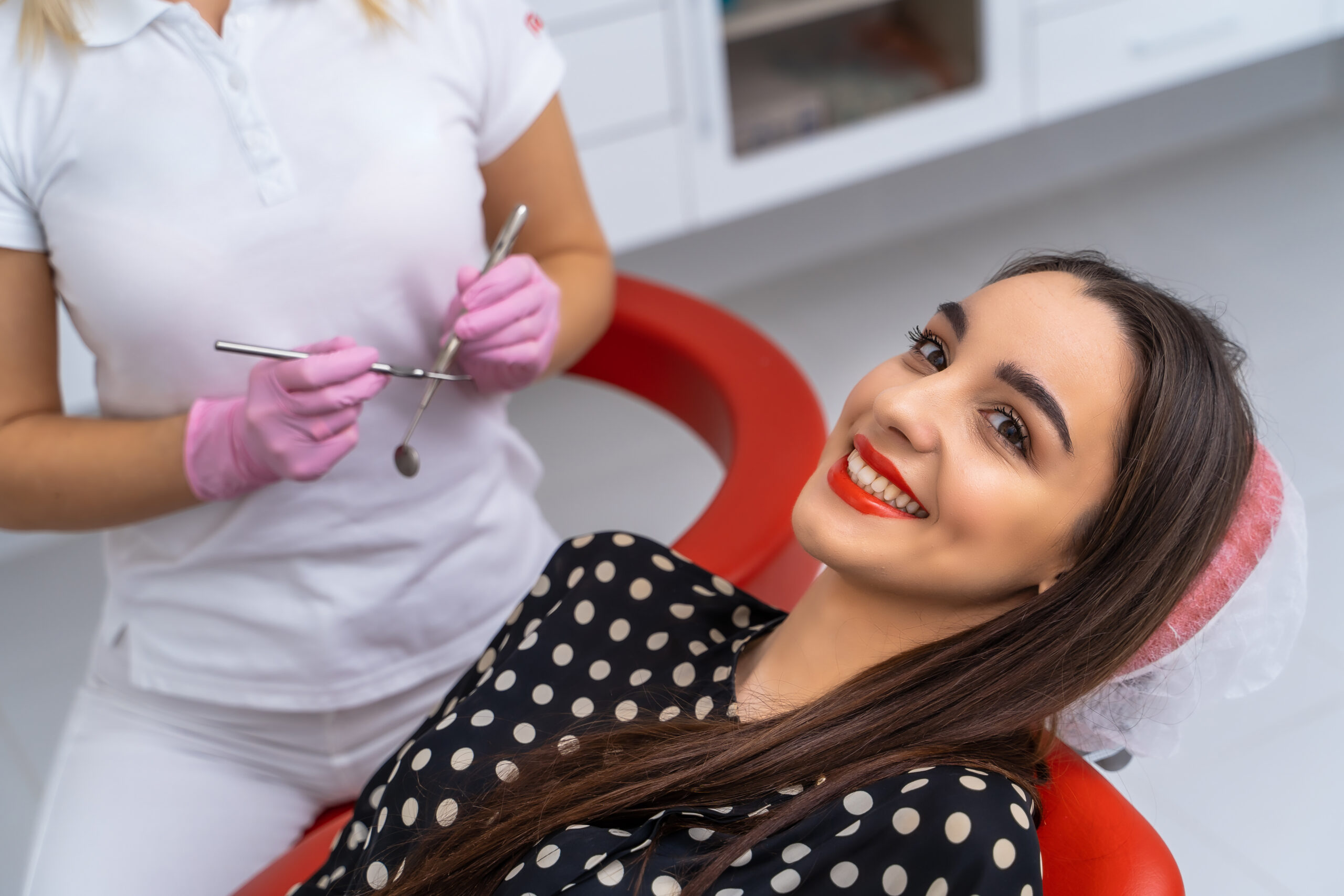 Young female patient visiting dentist office. Beautiful smiling woman with healthy straight white teeth sitting at dental chair. Dental clinic.Stomatology