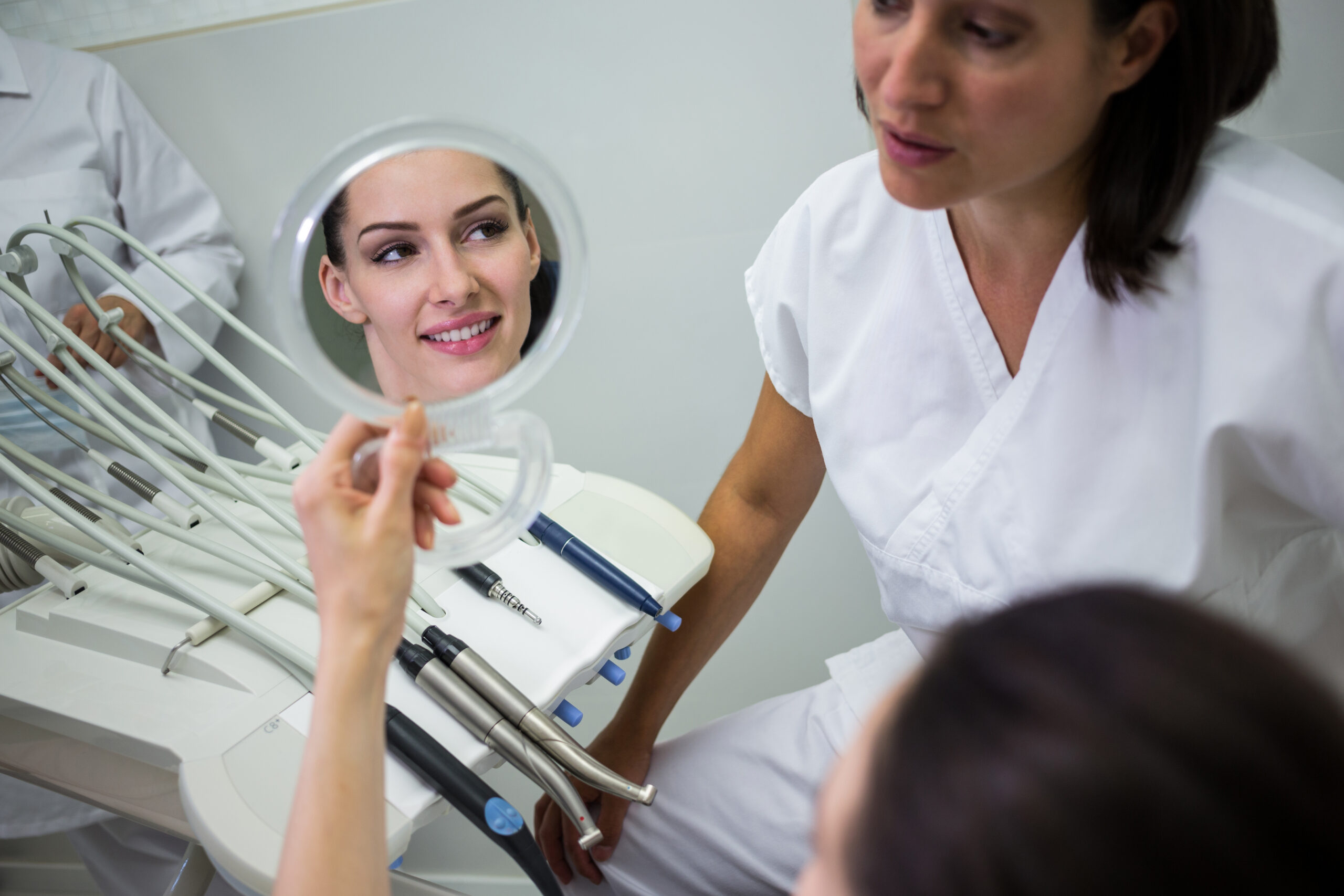Patient checking her teeth in mirror at dental clinic